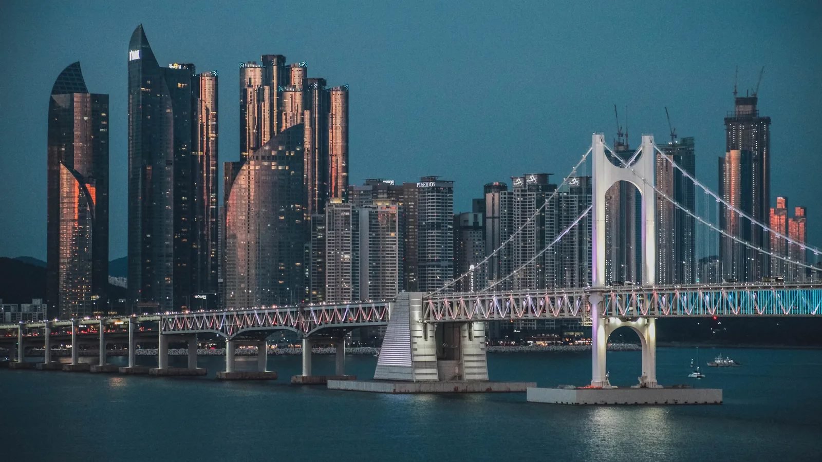 Illuminated Gwangan Bridge at night viewed against the Busan high-rise skyline