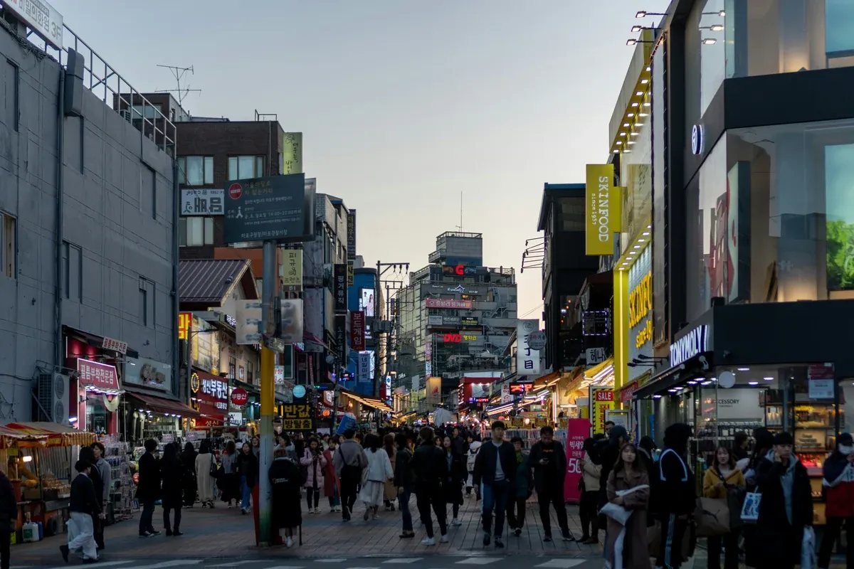 Busy Hongdae nightlife street in Seoul with neon signs and evening crowds