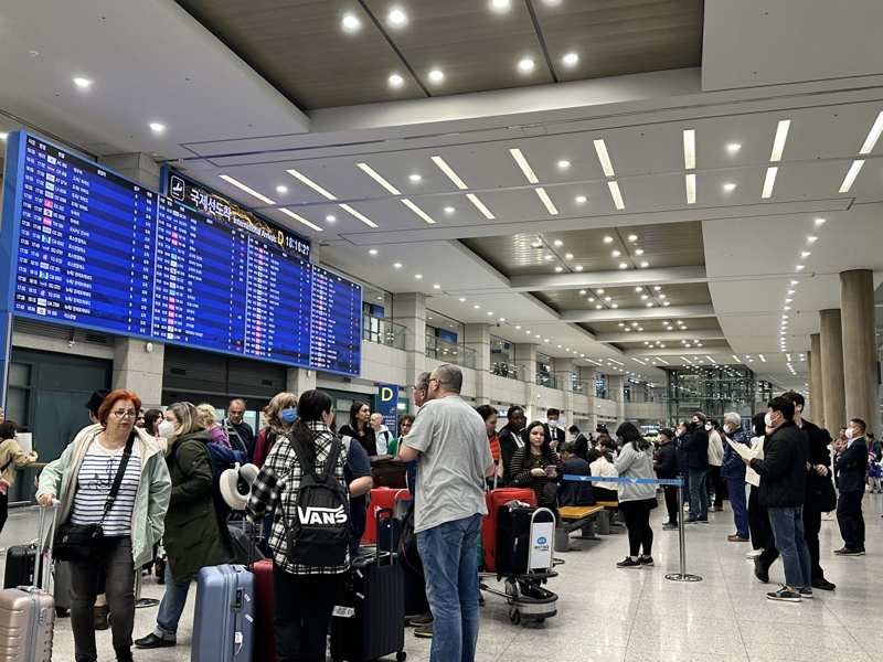 Travelers beneath flight information boards at Incheon International Airport