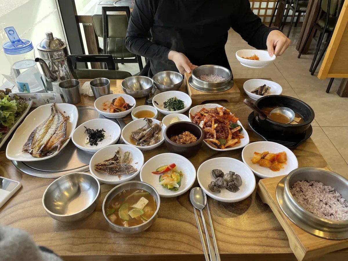 Traditional Korean dining table full of complimentary side dishes banchan, hot pot, and stone pot rice