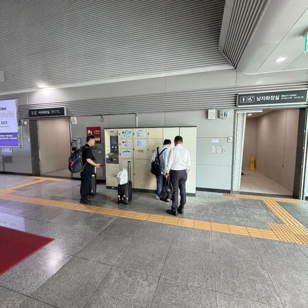 Travelers operating electronic luggage storage lockers at a Seoul transit station