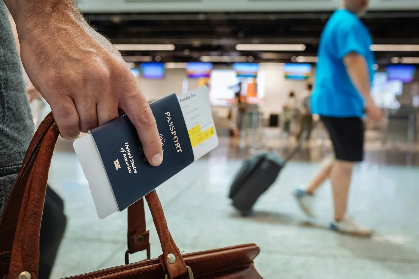 Traveler holding an international passport and boarding pass at an airport departure terminal
