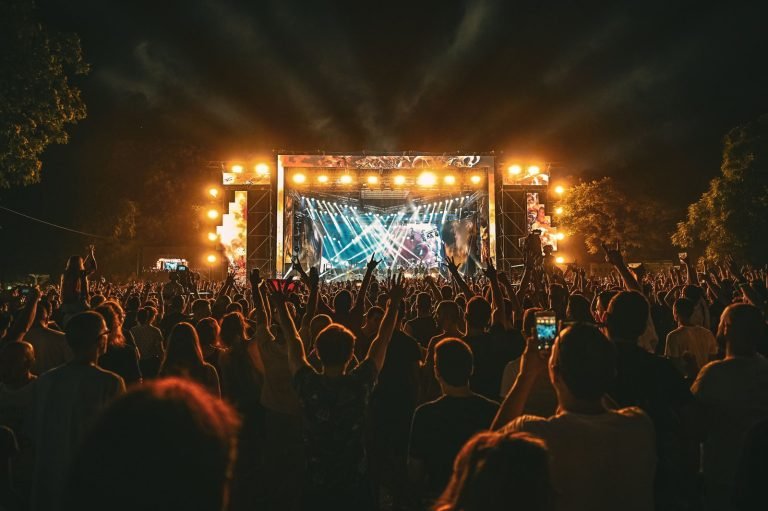 A large crowd watches an outdoor concert stage at night.