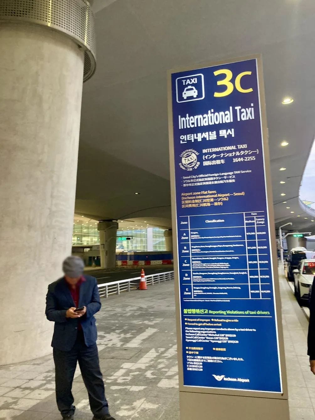 Blue International Taxi pickup sign marked 3C outside Incheon Airport Terminal 2.