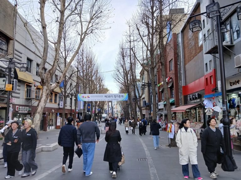 Pedestrians walking along the main Insadong-gil shopping street lined with shops.
