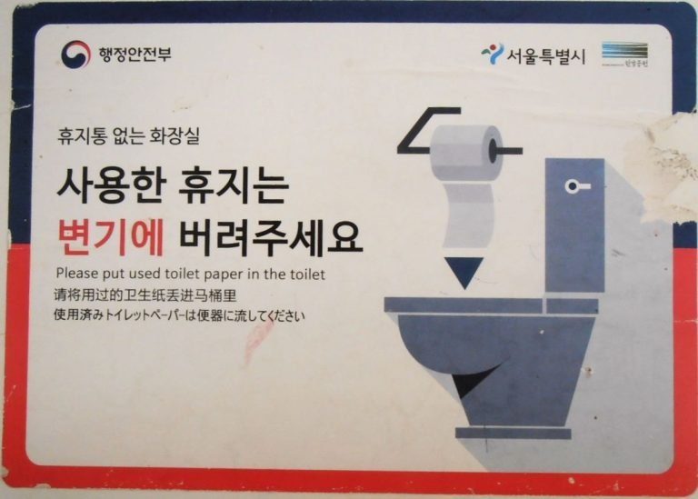 Sign explaining toilet paper disposal in a Korean public restroom