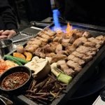 Samgyeopsal (pork belly) sizzling on a grill at a Korean BBQ restaurant.