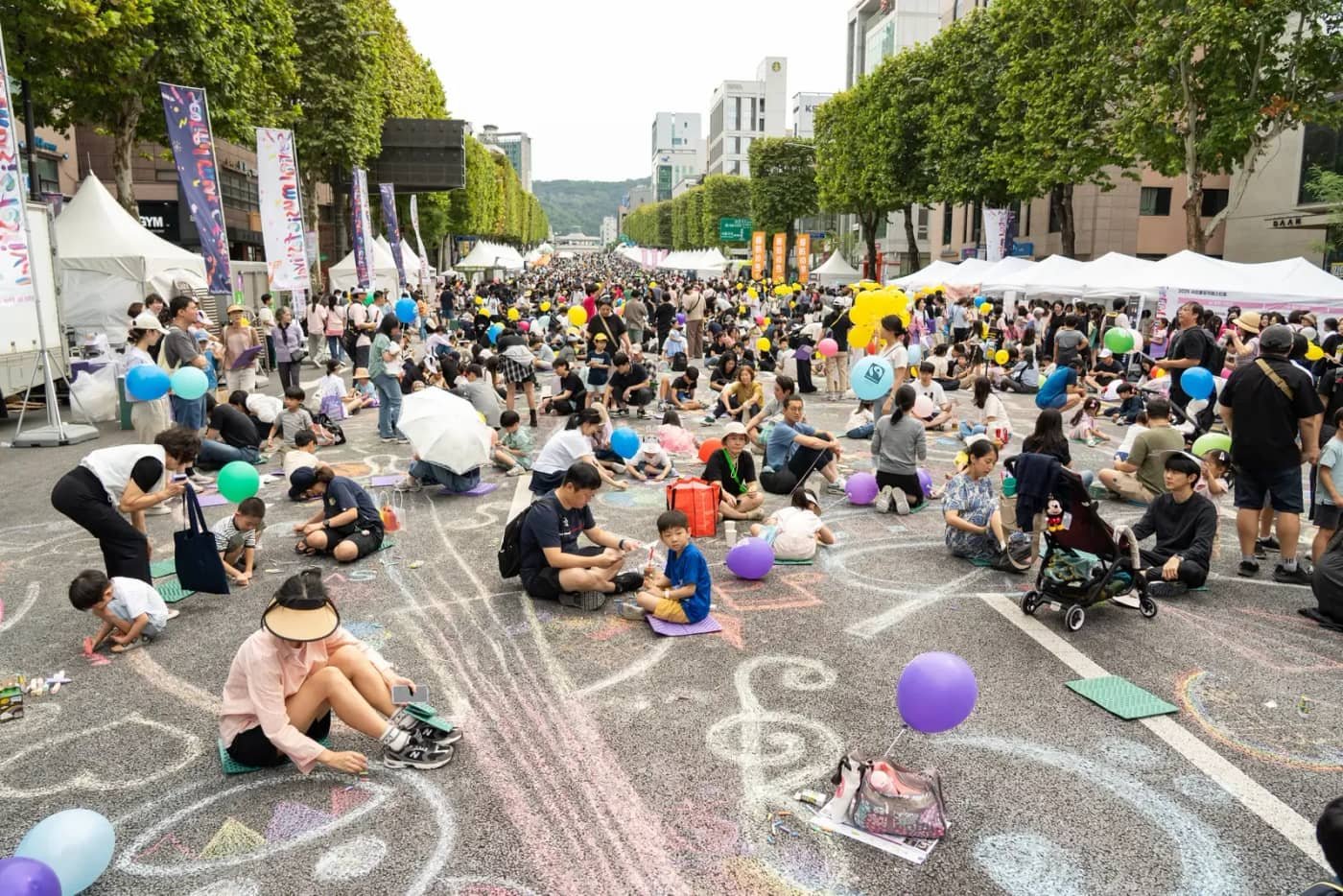 Families draw with colorful chalk across the car-free lanes of Banpo-daero during the 2025 Seoripul Music Festival.