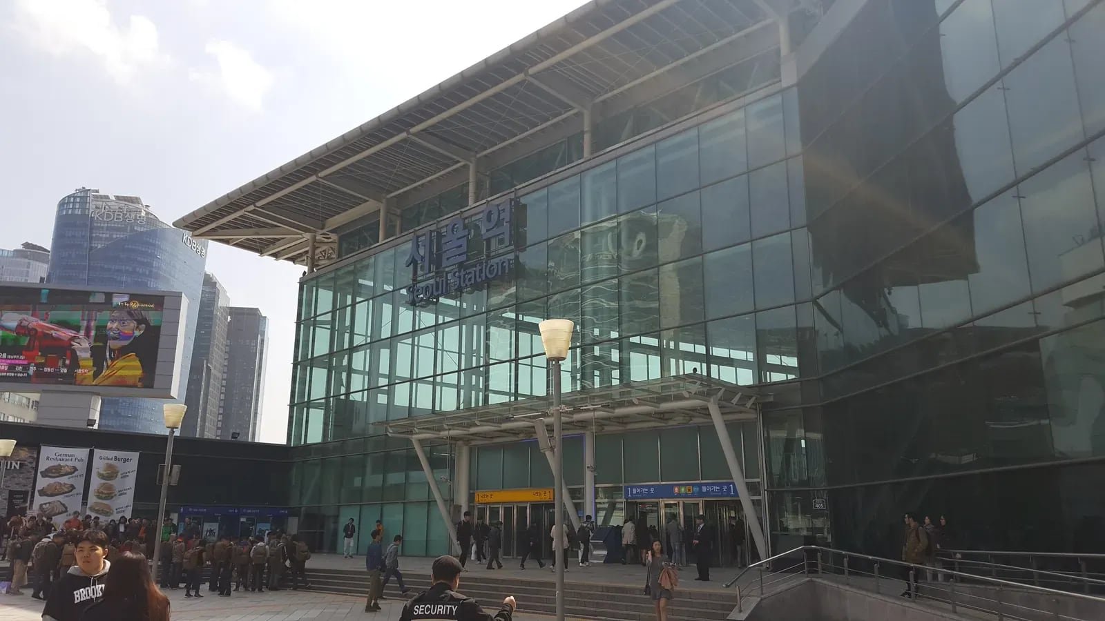 Glass-fronted entrance to Seoul Station's passenger terminal, with travelers outside