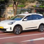 White Kia Niro Plus electric taxi on a street in Seoul.